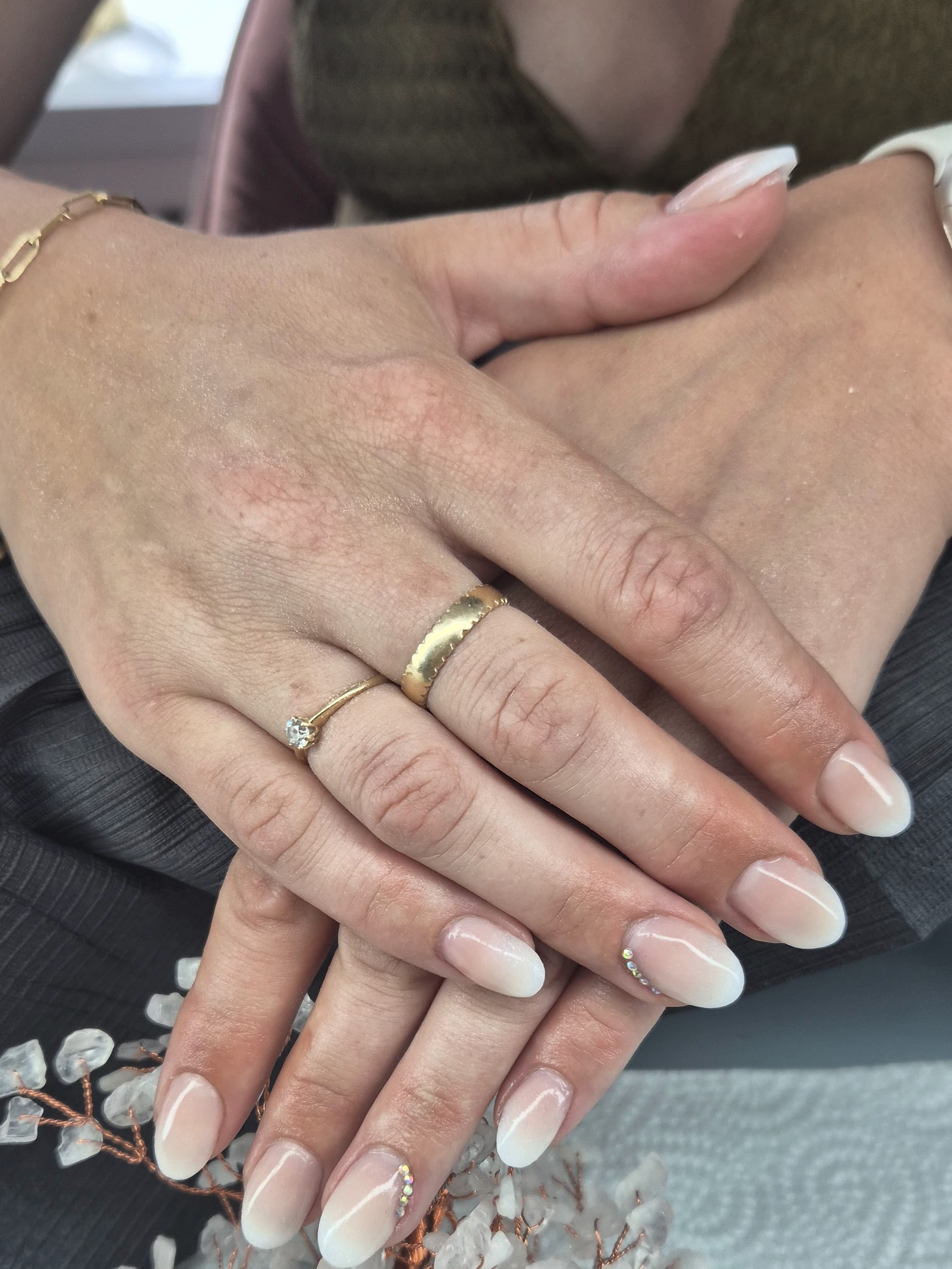 Handen met naturel amandelvormige nagels met french fade en een steentje