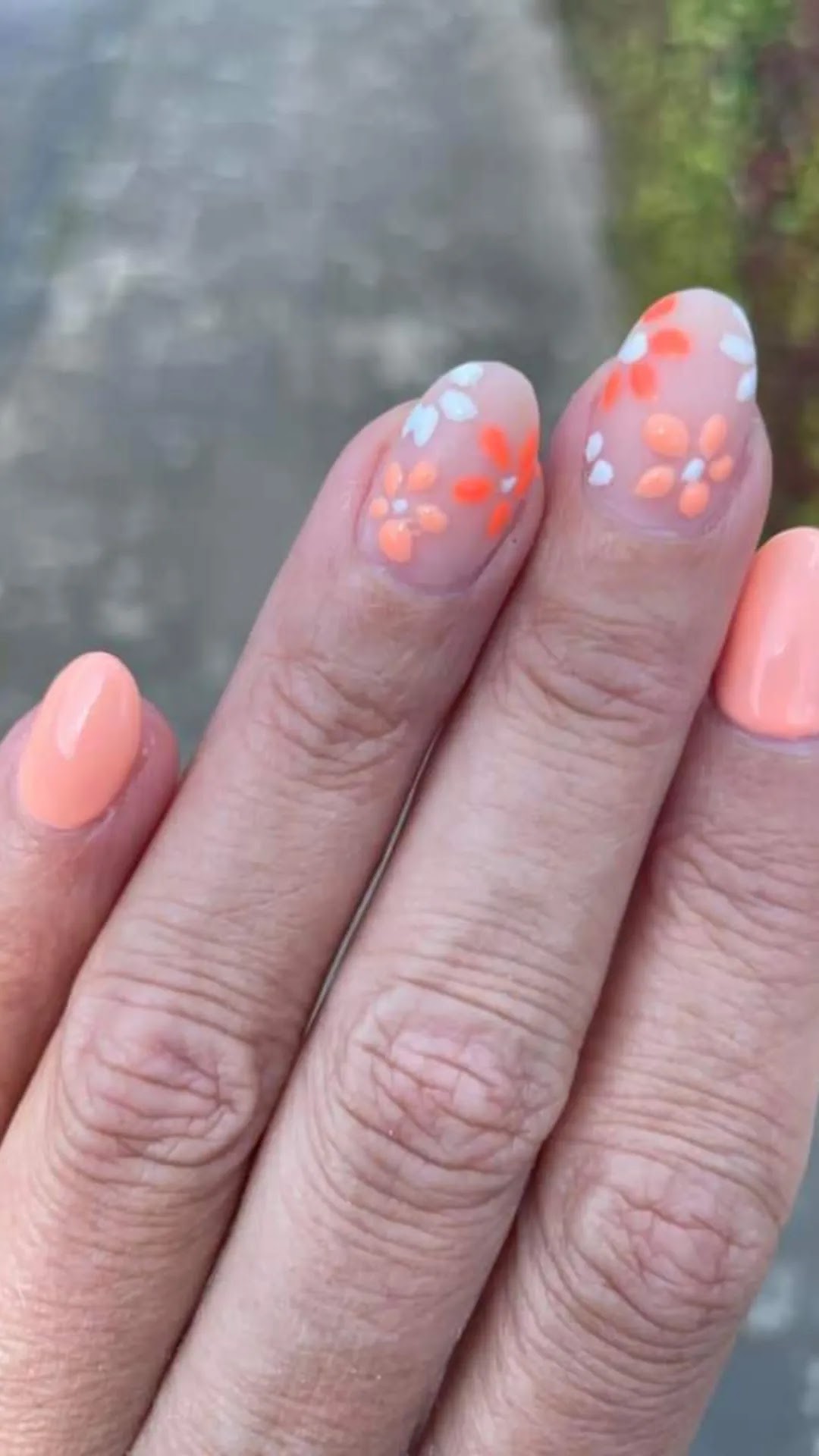 Perzikkleurige set met oranje en witte bloemen op de accentnagels